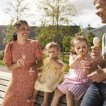Woman, man and 2 ckids eating ice cream next to the urban beach