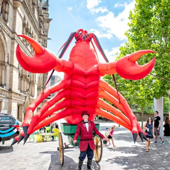 A performer pulling a cart with a giant lobster on the back